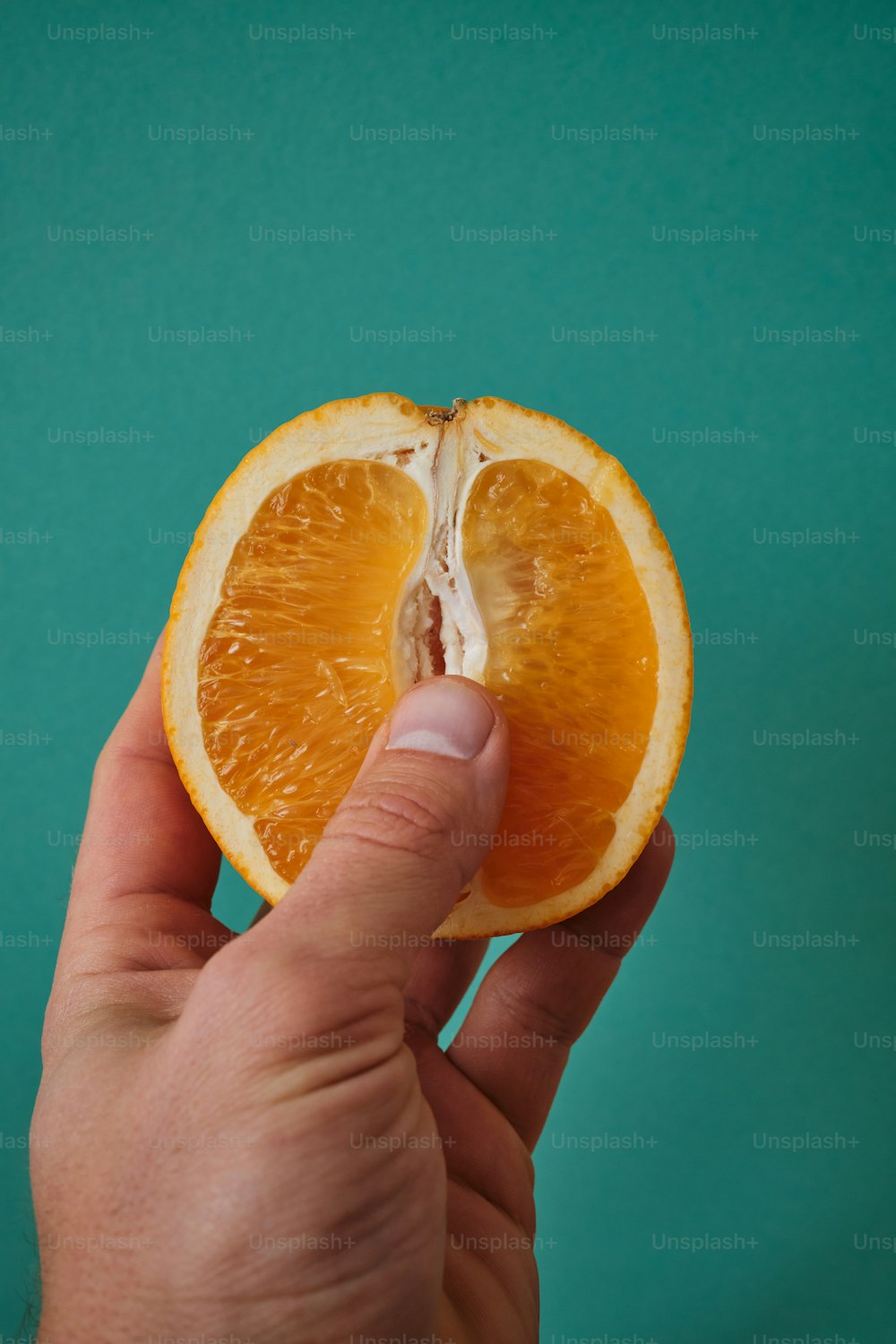 a hand holding a half of an orange