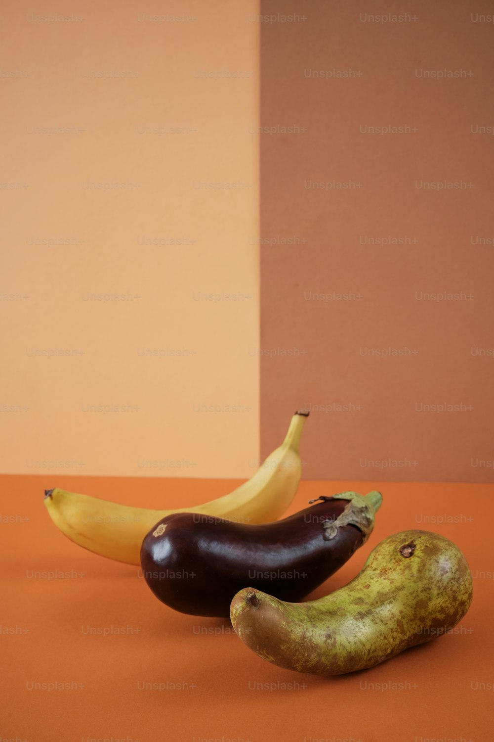 two eggplant and a banana sitting on a table