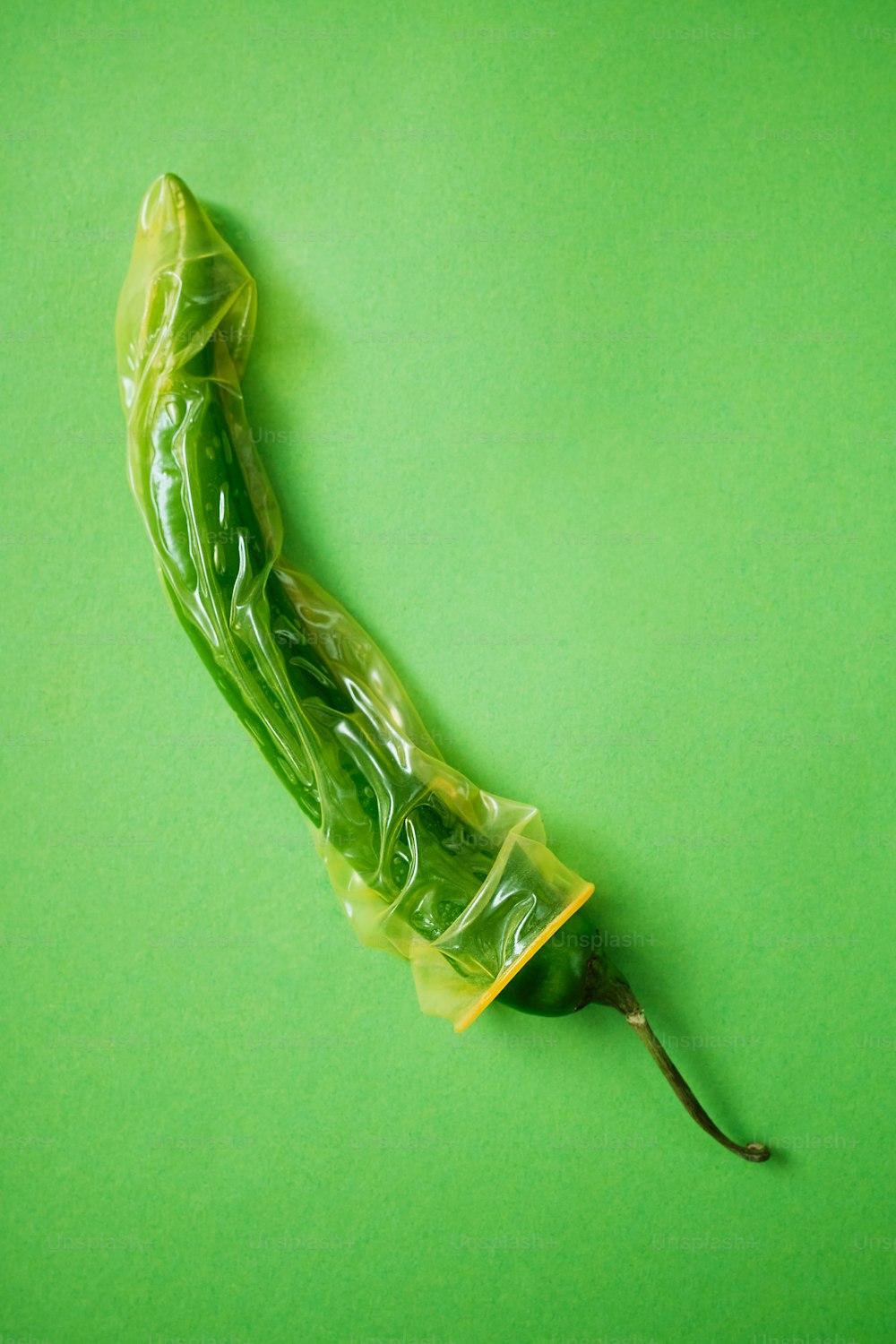 ein grünes Gemüse, das in Plastik eingewickelt ist, auf grünem Hintergrund