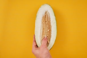 a person is holding a half of a melon