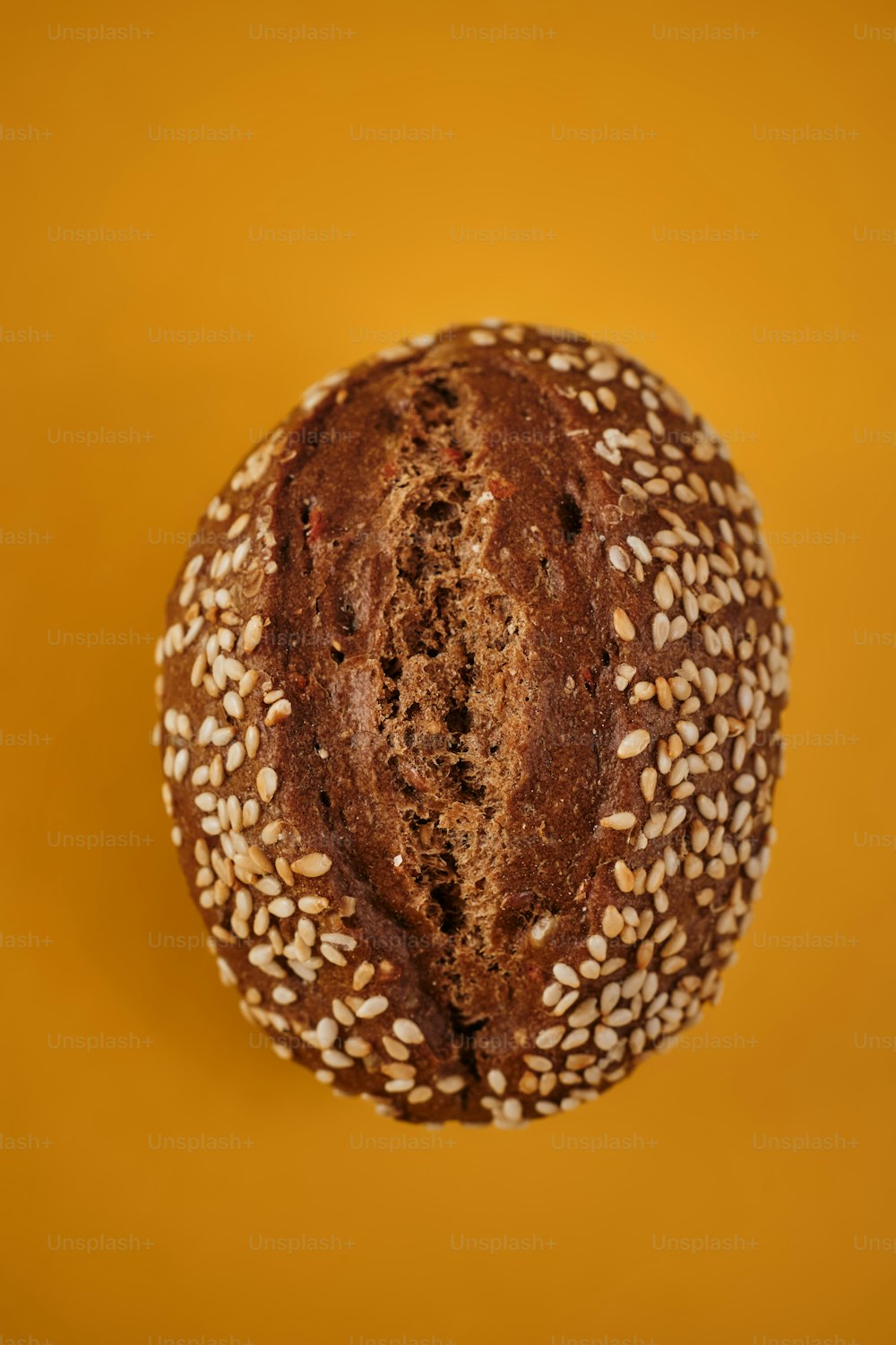 ein Laib Brot mit Sesam auf gelbem Hintergrund