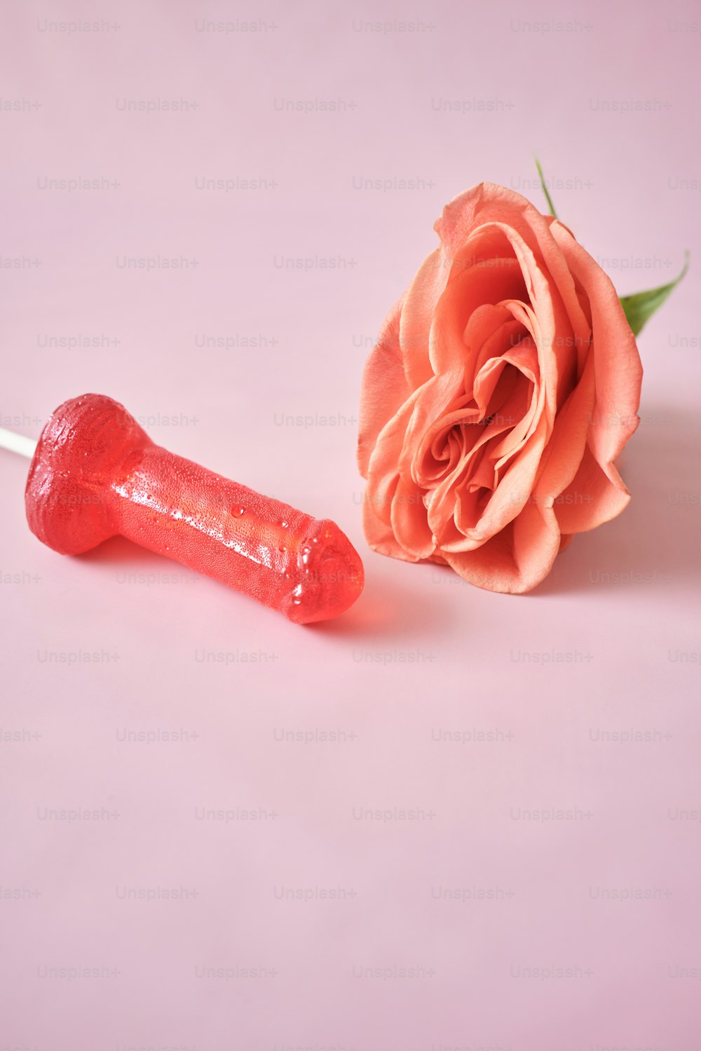 una rosa y una barra de chocolate sobre un fondo rosa