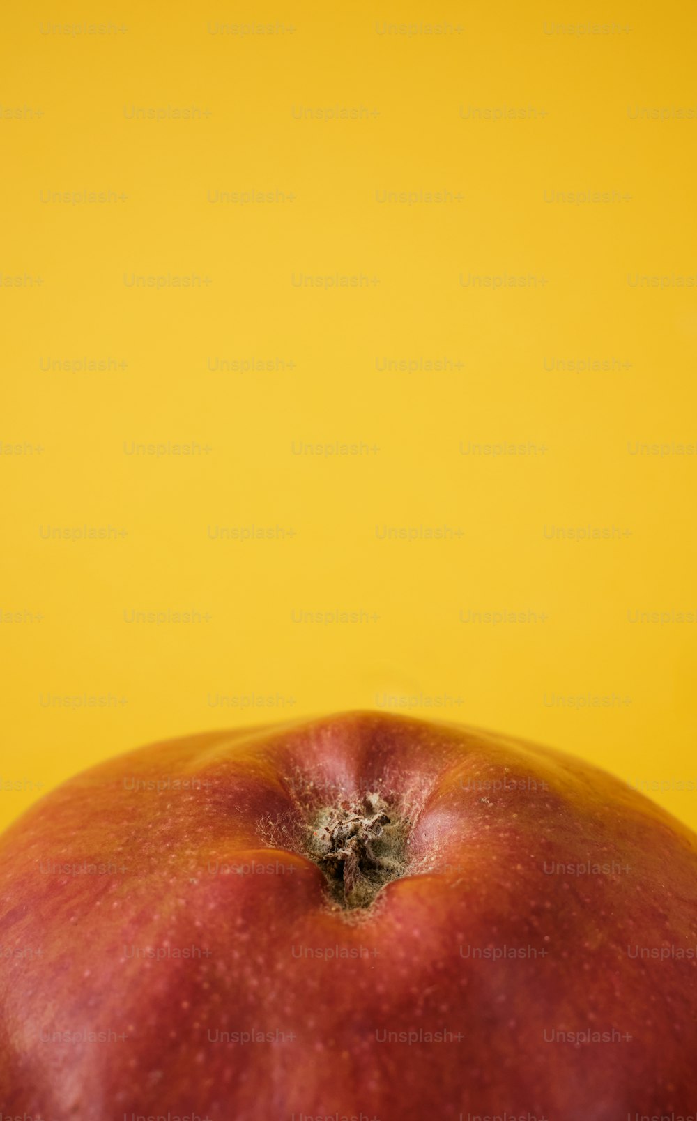 a red apple sitting on top of a yellow table