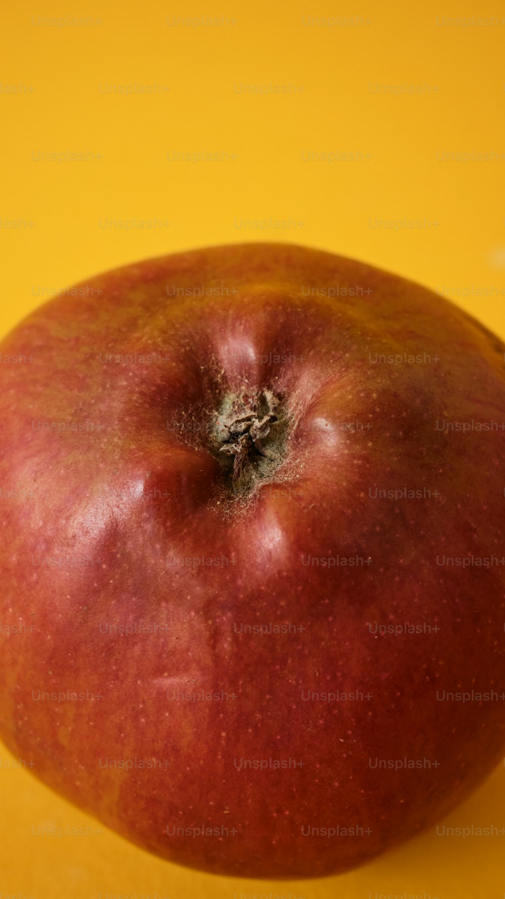 a red apple sitting on top of a yellow table