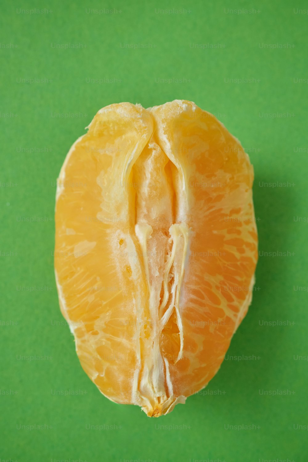 a peeled orange sitting on top of a green surface