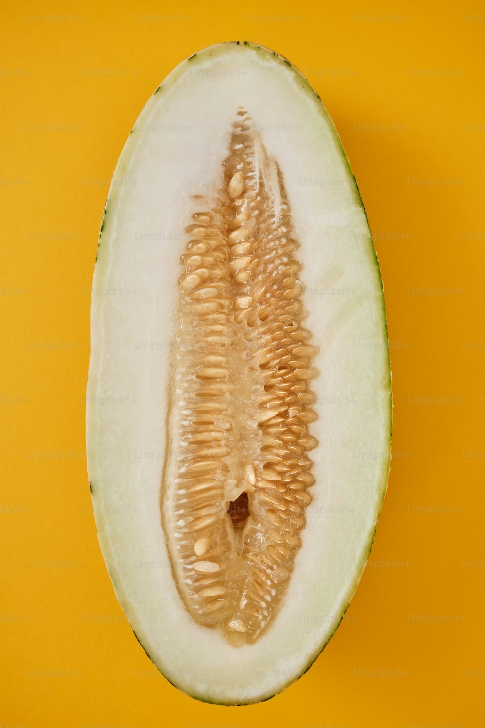 a cut in half melon on a yellow background