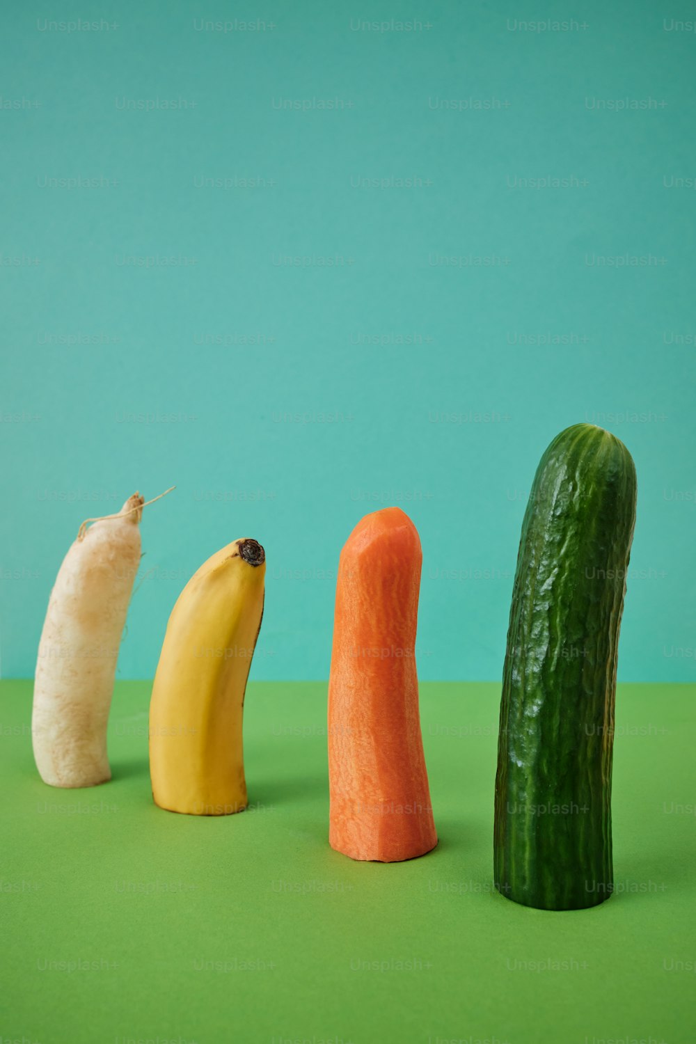 a cucumber, banana, and carrot are arranged in a row