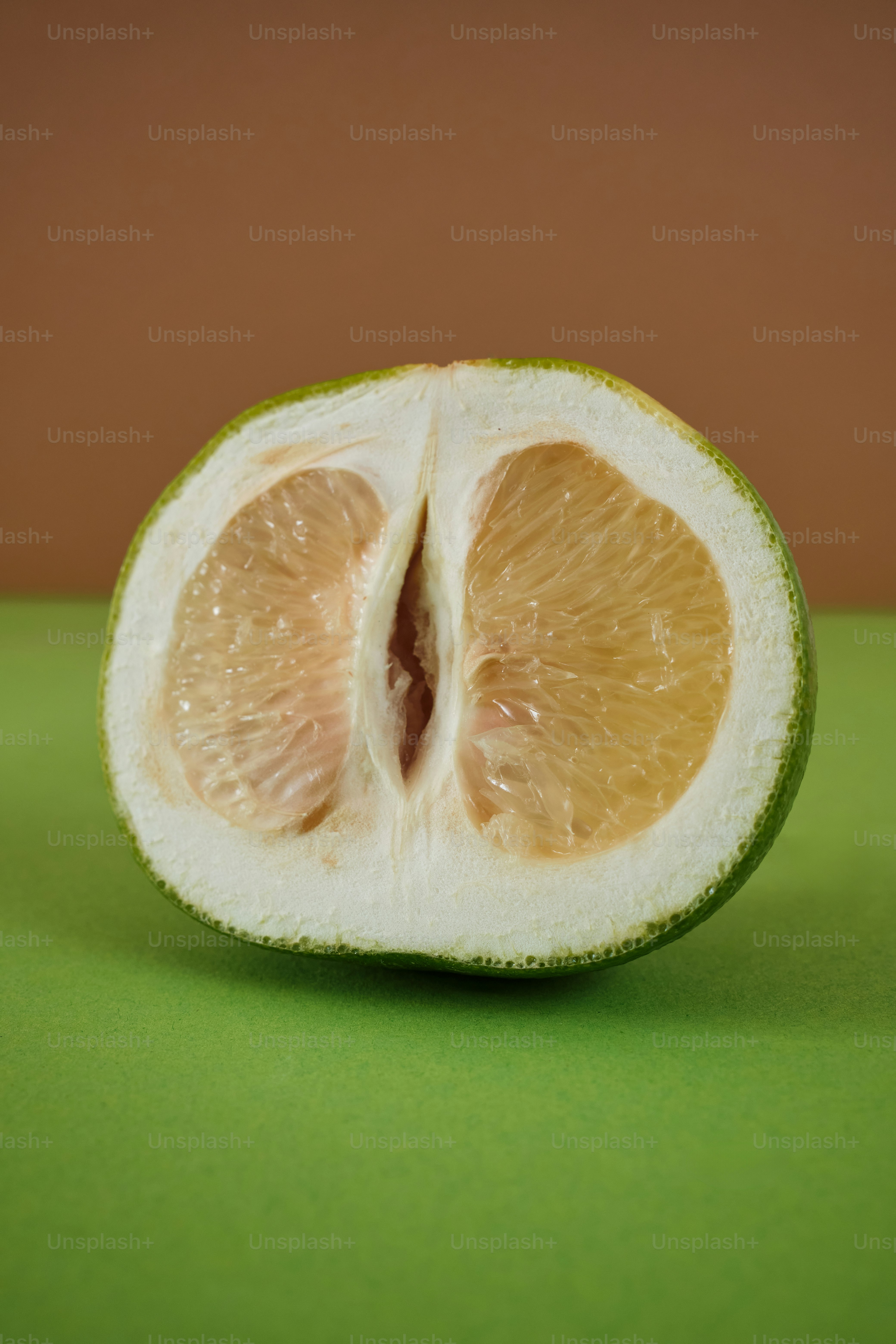 una naranja a medio comer sentada encima de una mesa verde