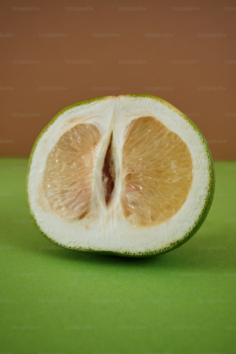 Eine halb gegessene Orange sitzt auf einem grünen Tisch