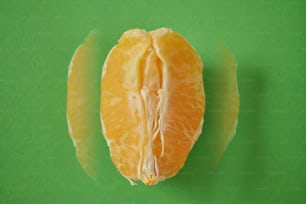 eine geschälte Orange, die auf einer grünen Oberfläche sitzt