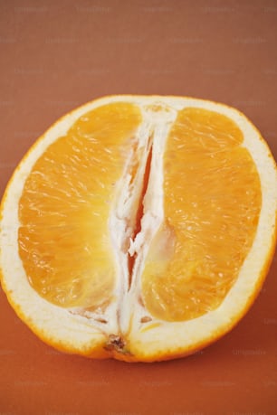 an orange cut in half on a brown surface