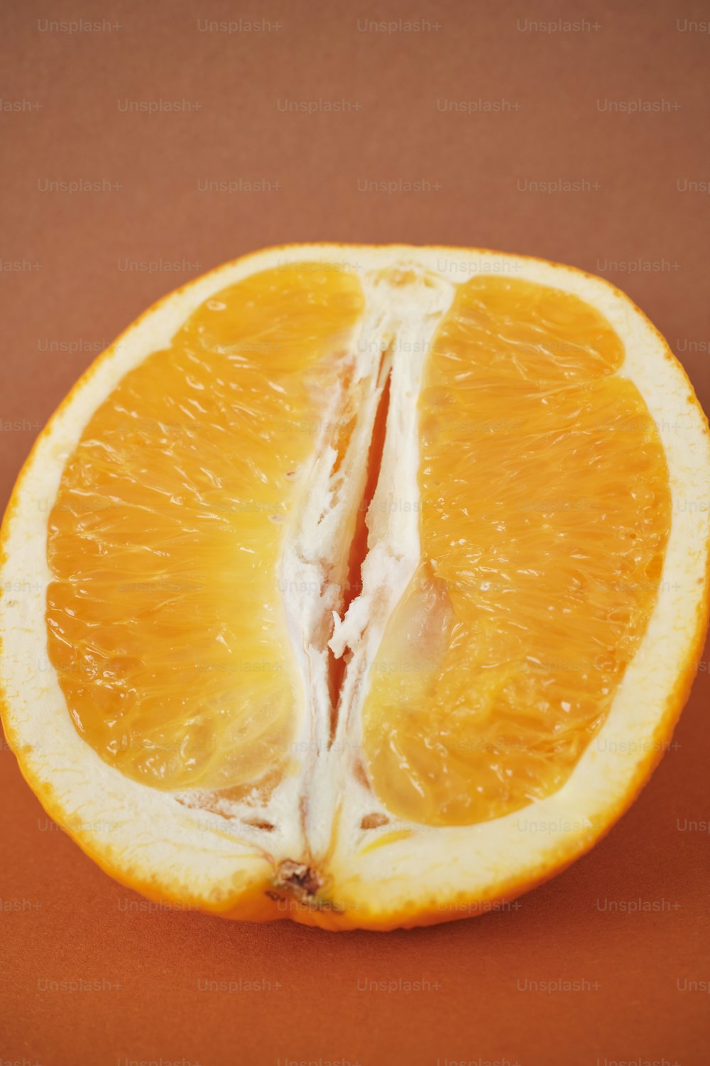 une orange coupée en deux sur une surface brune