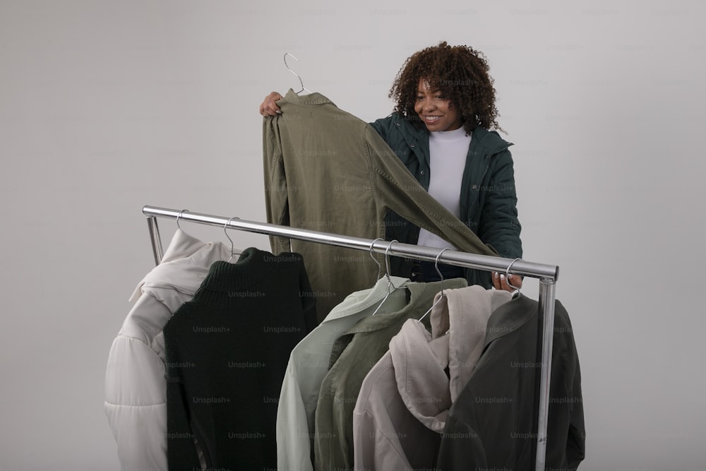 a woman standing next to a rack of clothes