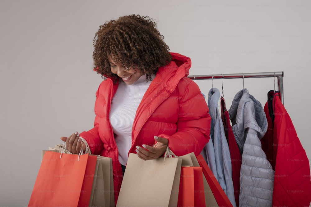 a woman in a red jacket holding shopping bags