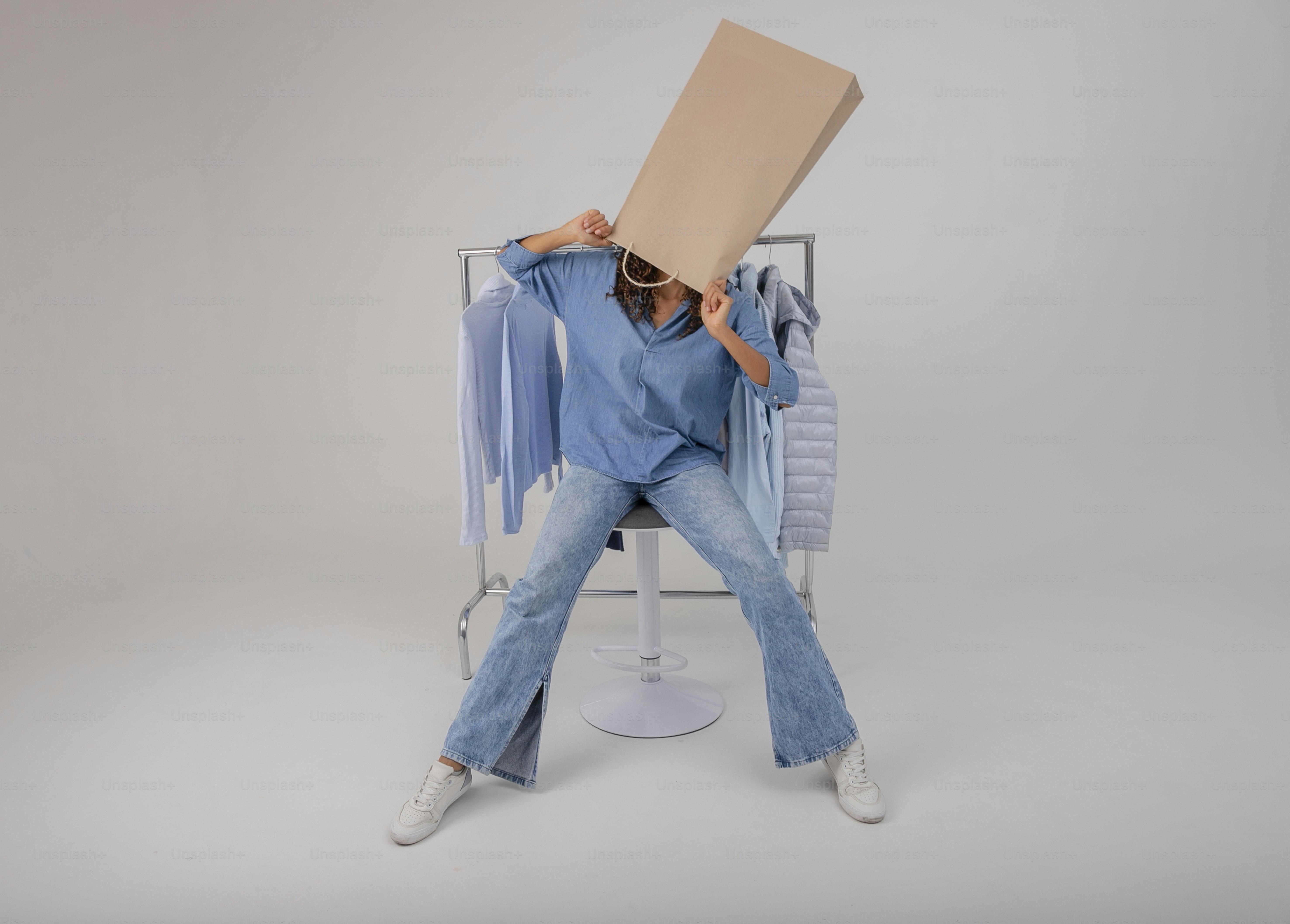 A woman sitting on a chair holding a cardboard box over her head photo ...