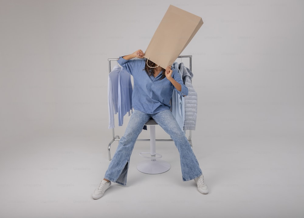 a woman sitting on a chair holding a cardboard box over her head
