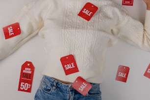 a woman wearing a white sweater with red sale tags on it
