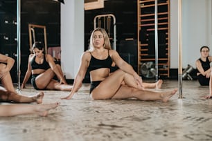 Eine Gruppe von Frauen, die in einem Fitnessstudio auf dem Boden sitzen