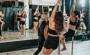 a group of women doing pole dancing in front of a mirror
