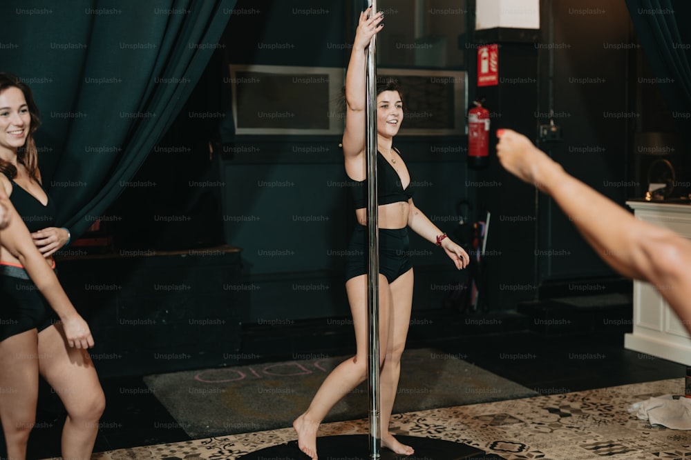 a woman in a black bathing suit standing next to a pole