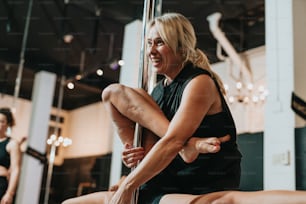 a woman sitting on a pole in a gym