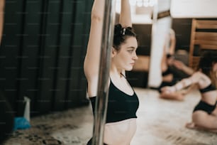a woman in a black top is doing exercises on a pole