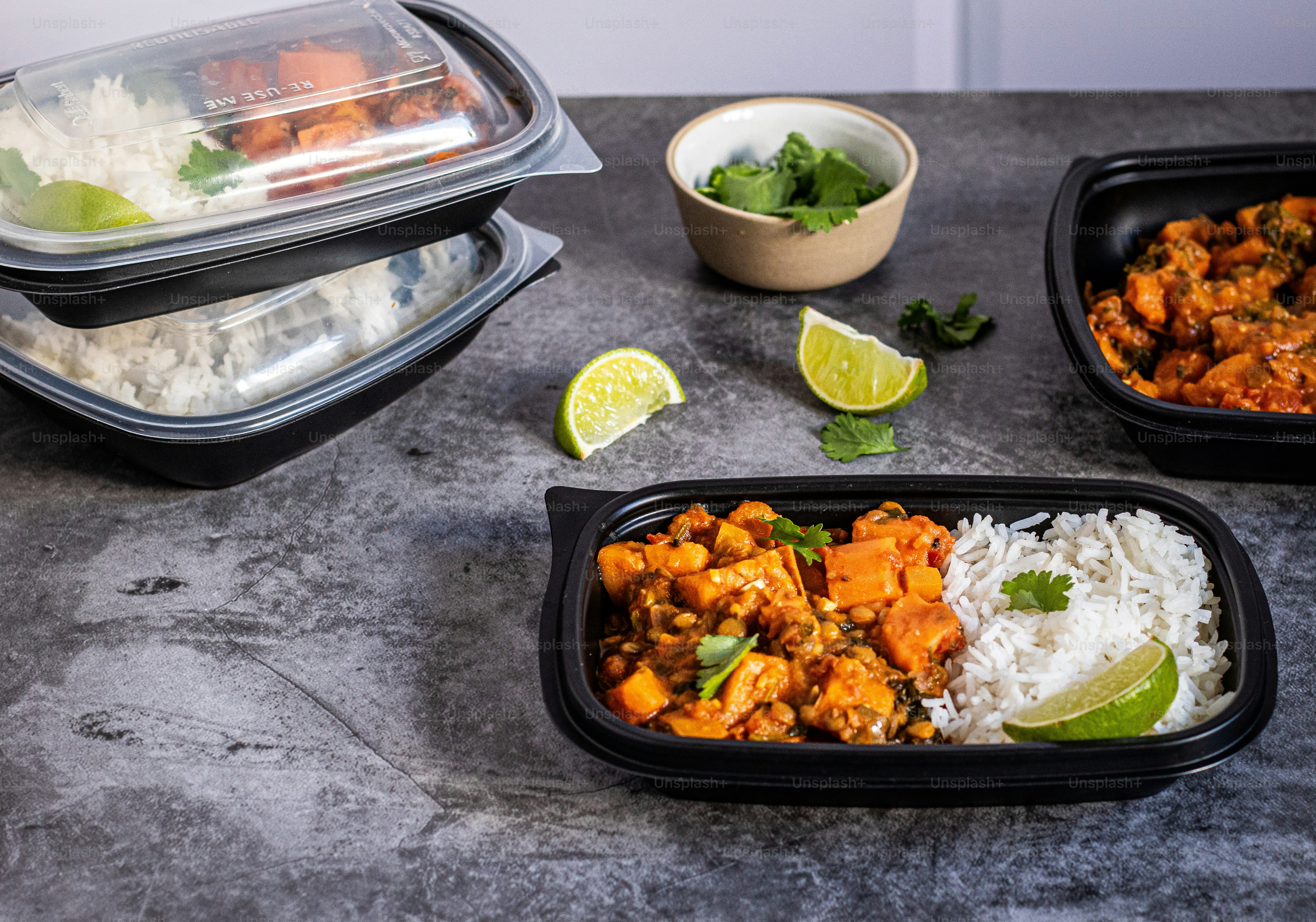 a table topped with containers of food and a bowl of rice