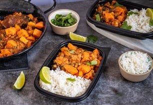 a table topped with containers of food and bowls of rice