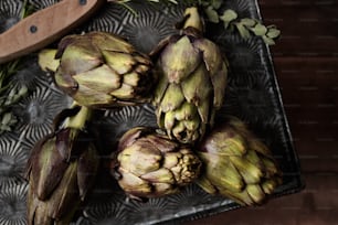 a bunch of artichokes sitting on top of a metal tray