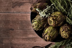a bowl of artichokes on a wooden table