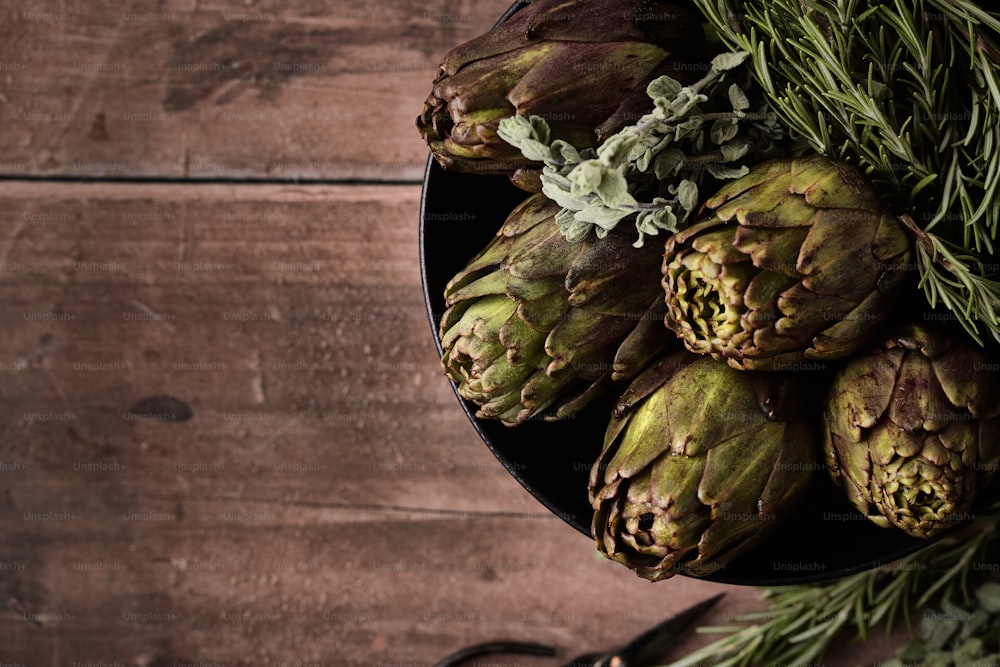 a bowl of artichokes on a wooden table