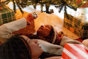 a woman laying on the floor next to a christmas tree