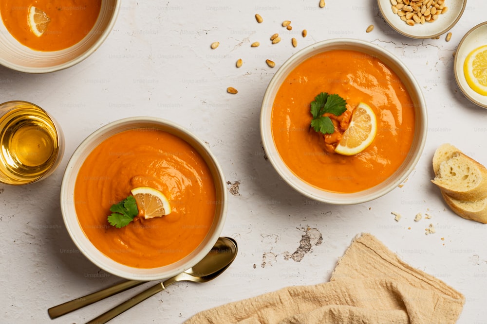 two bowls of carrot soup with a slice of lemon on top