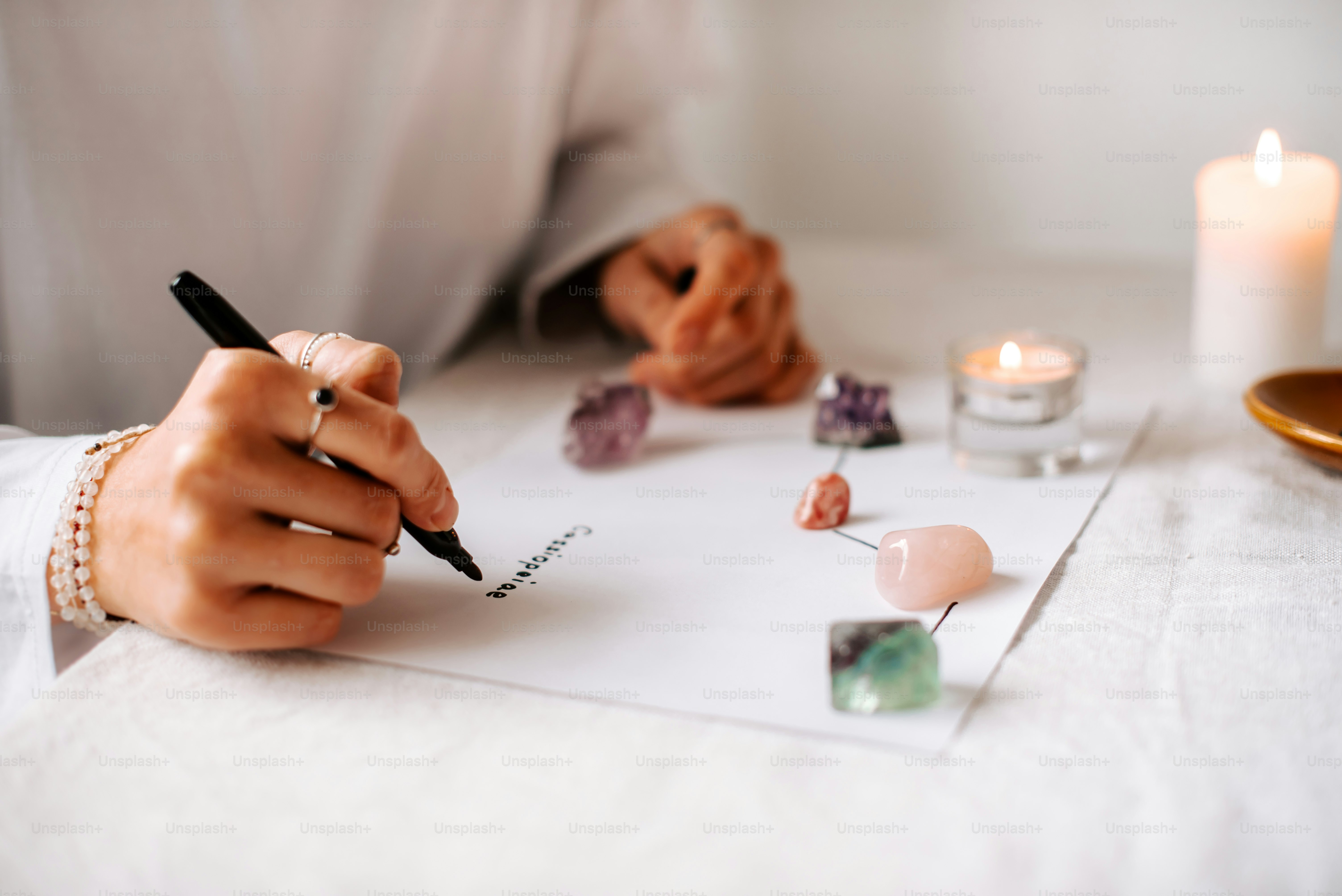 una persona escribiendo en un pedazo de papel con una vela en el fondo
