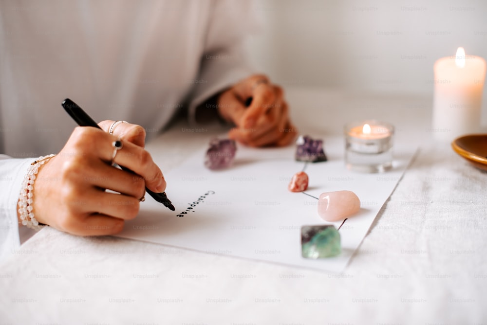 a person writing on a piece of paper with a candle in the background
