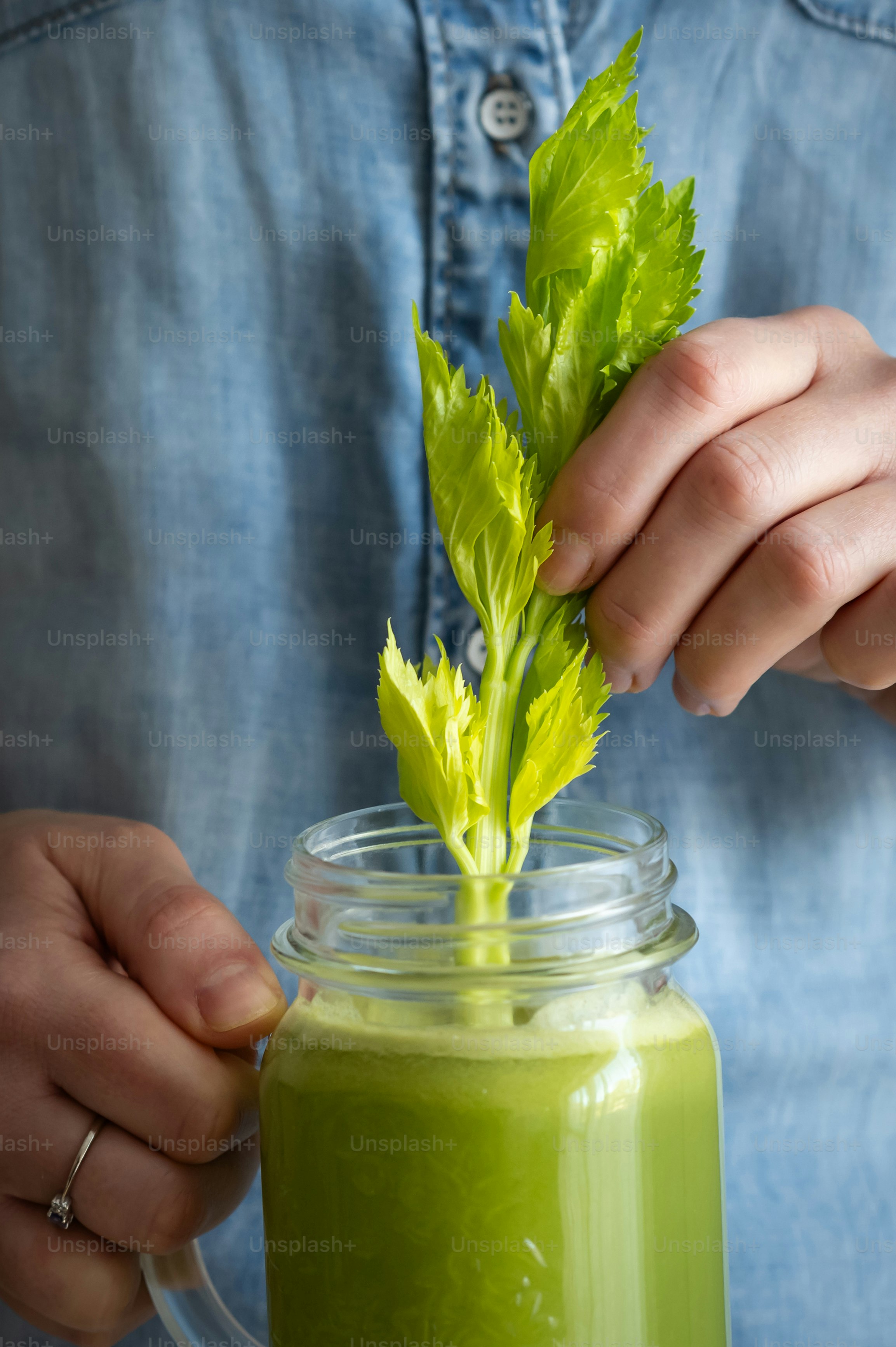 a person holding a green drink in a mason jar