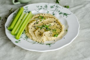 a white plate topped with hummus and celery sticks