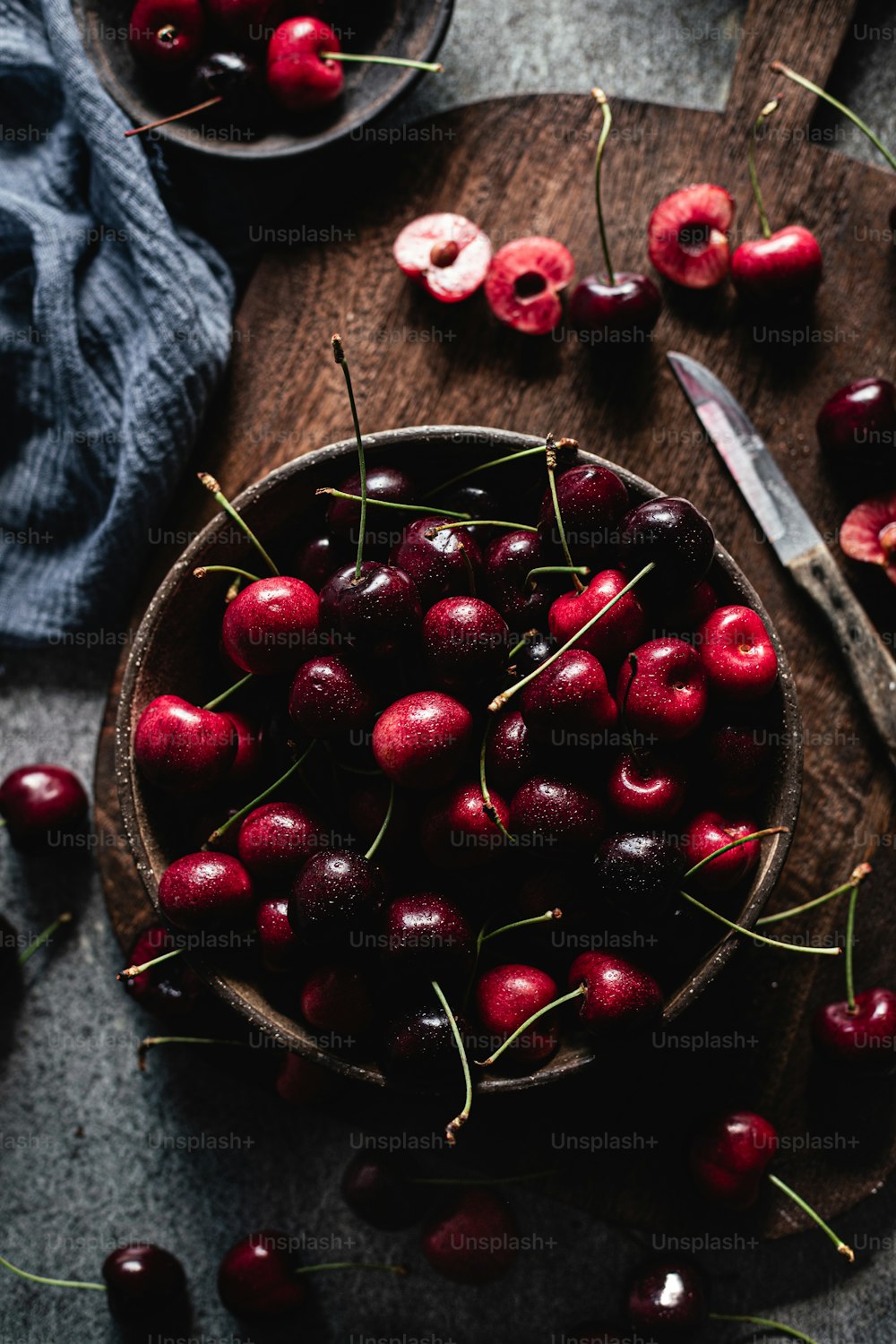 a wooden bowl filled with cherries on top of a table