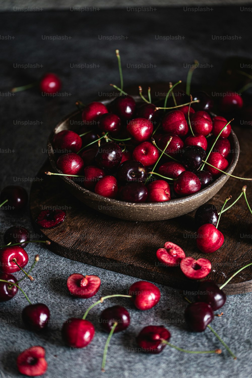 a wooden bowl filled with cherries on top of a table