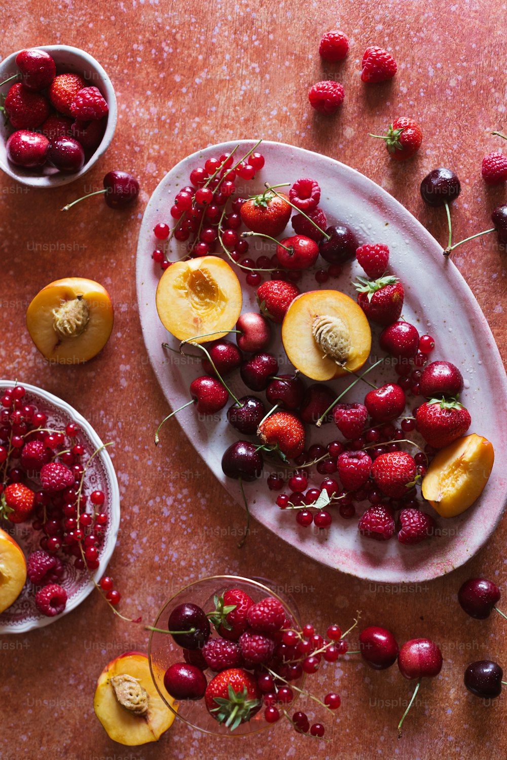 un plato de cerezas, duraznos y fresas sobre una mesa