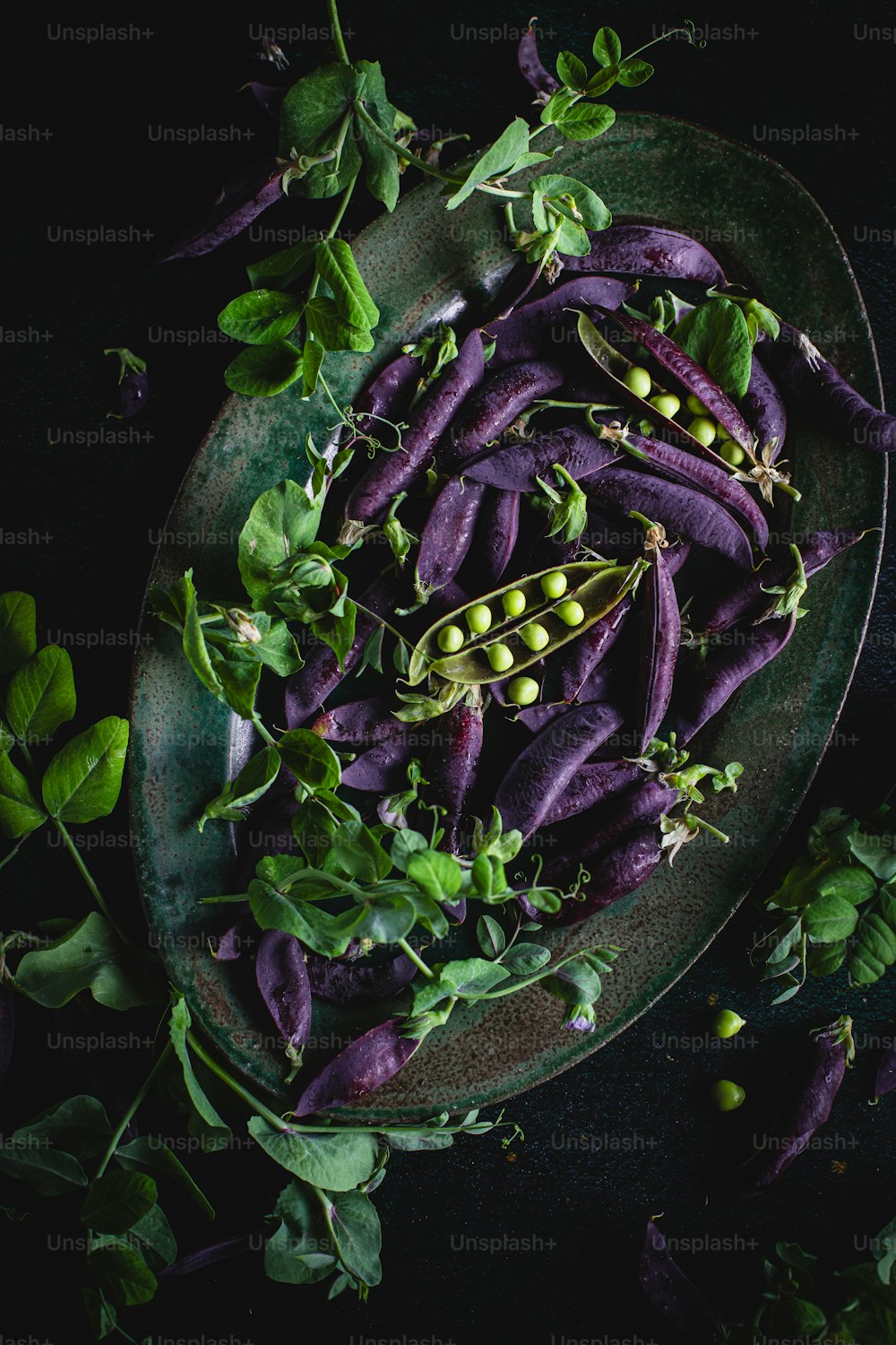 a plate of purple beans and green leaves