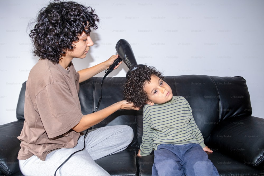 a woman blow drying a young boy's hair