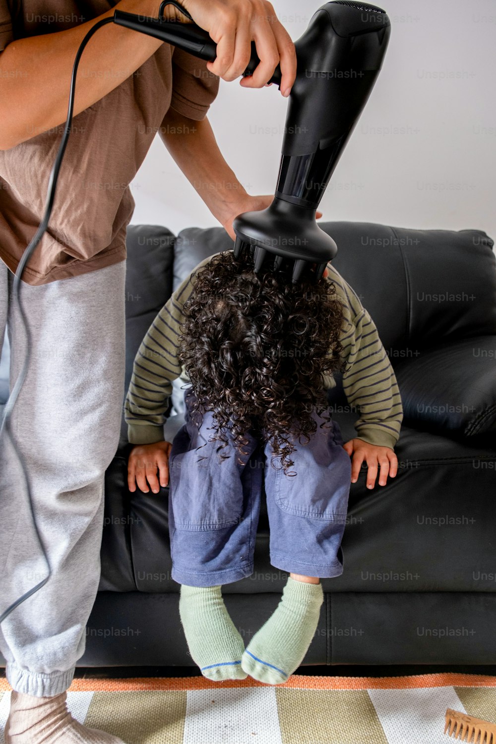 Una mujer secando el cabello de un niño con un secador de pelo