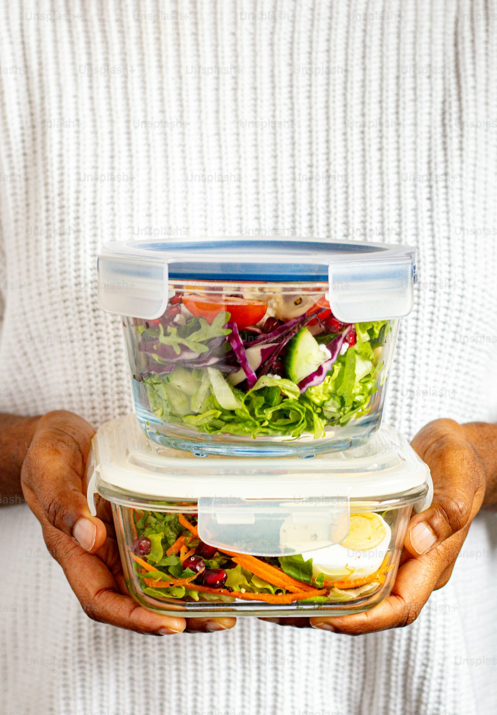 a person holding a container with a salad in it