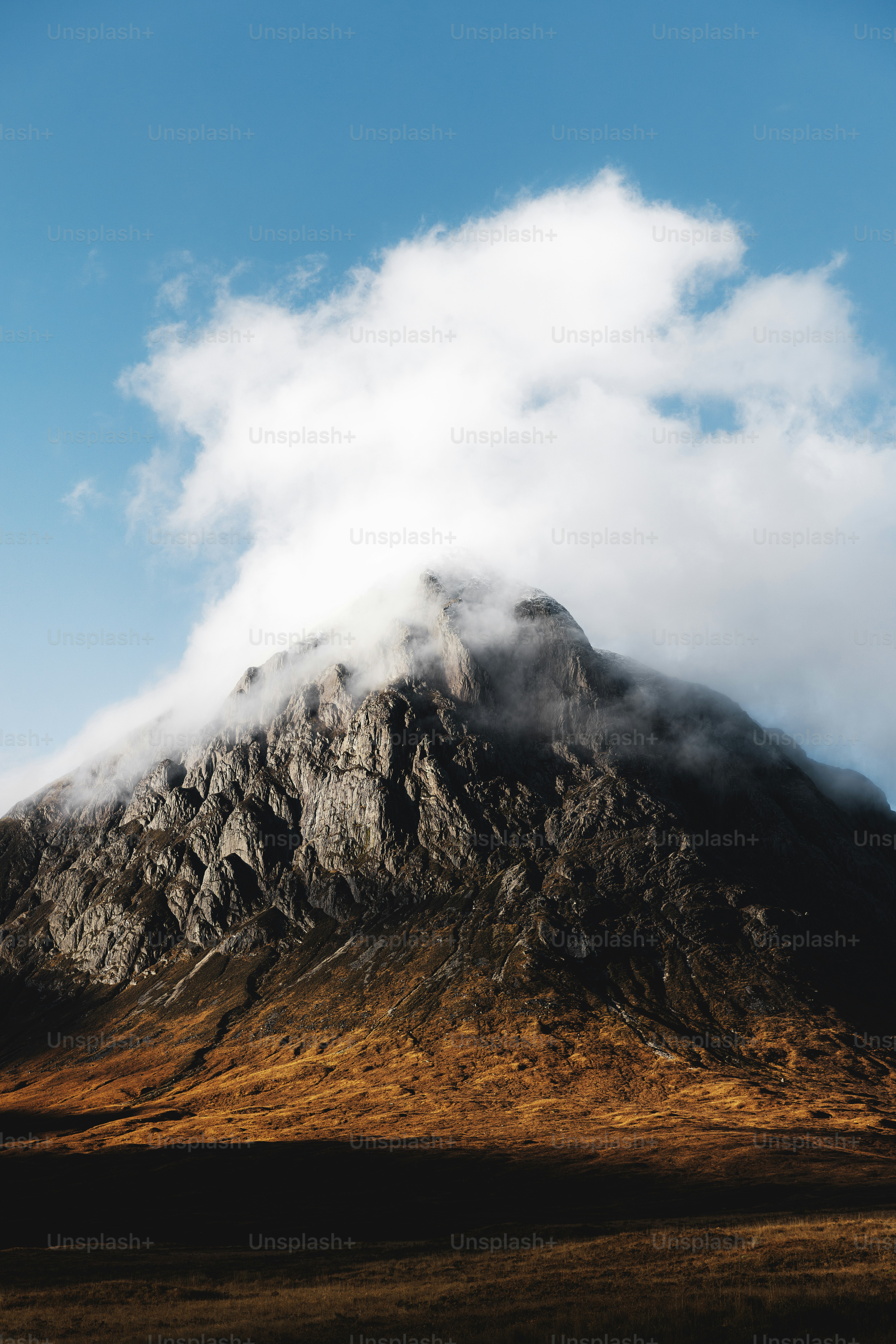 a very tall mountain with some clouds in the sky