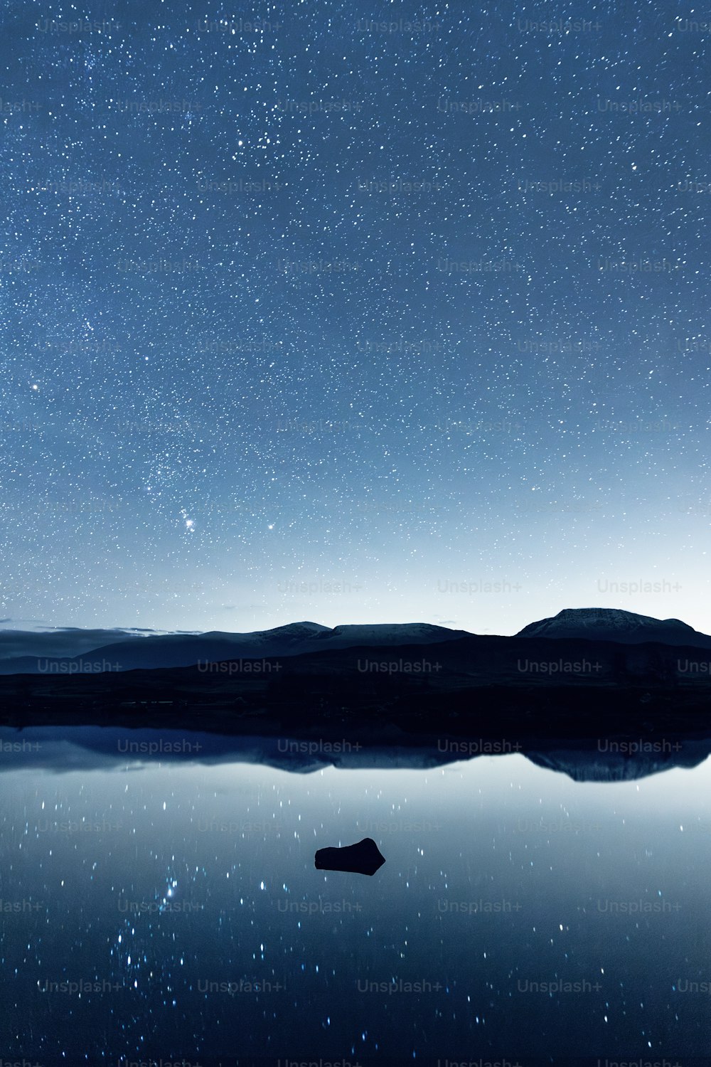 a body of water under a night sky filled with stars