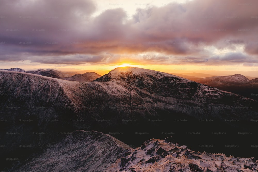 the sun is setting over a mountain range