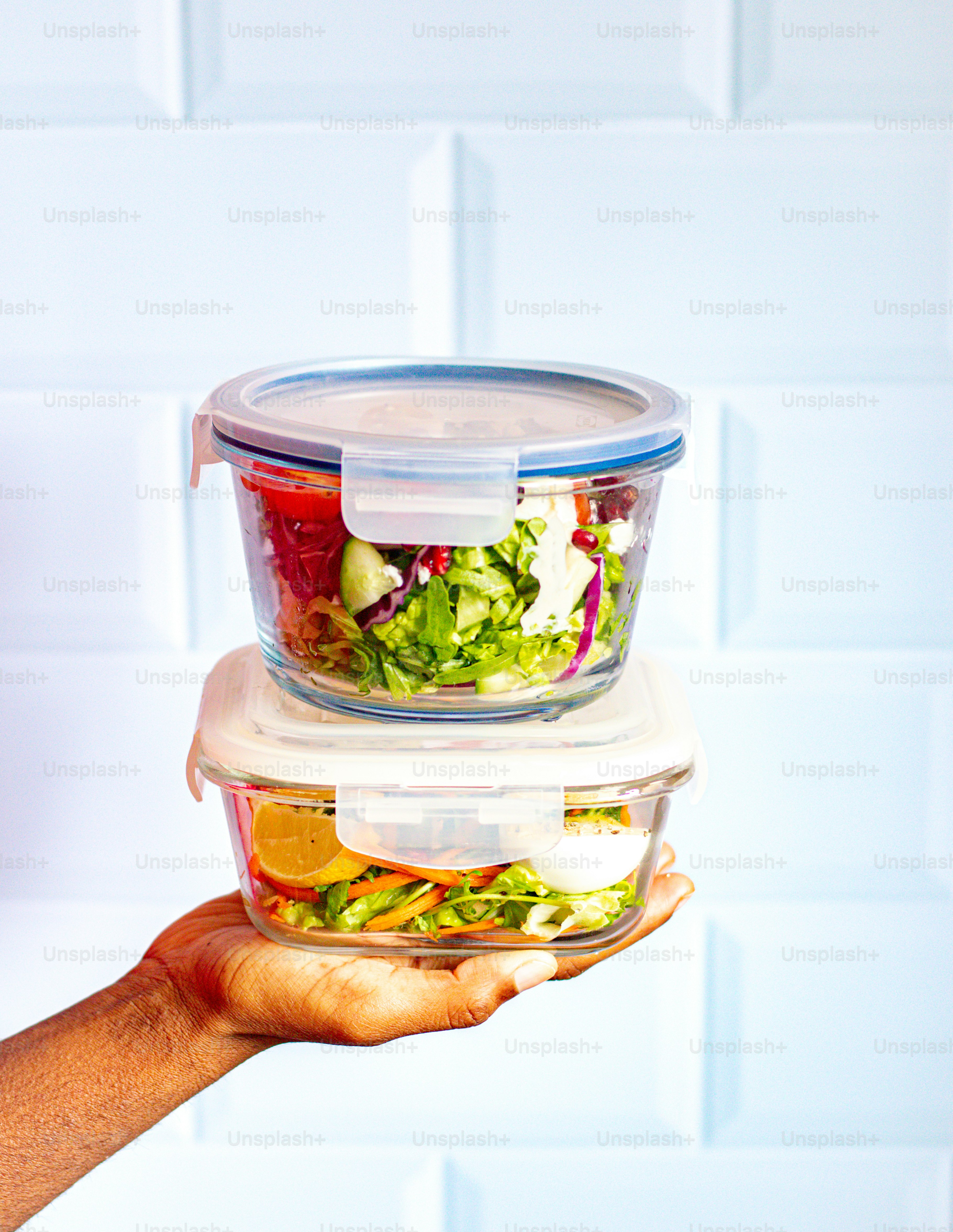 una persona che tiene in mano due contenitori di plastica pieni di cibo