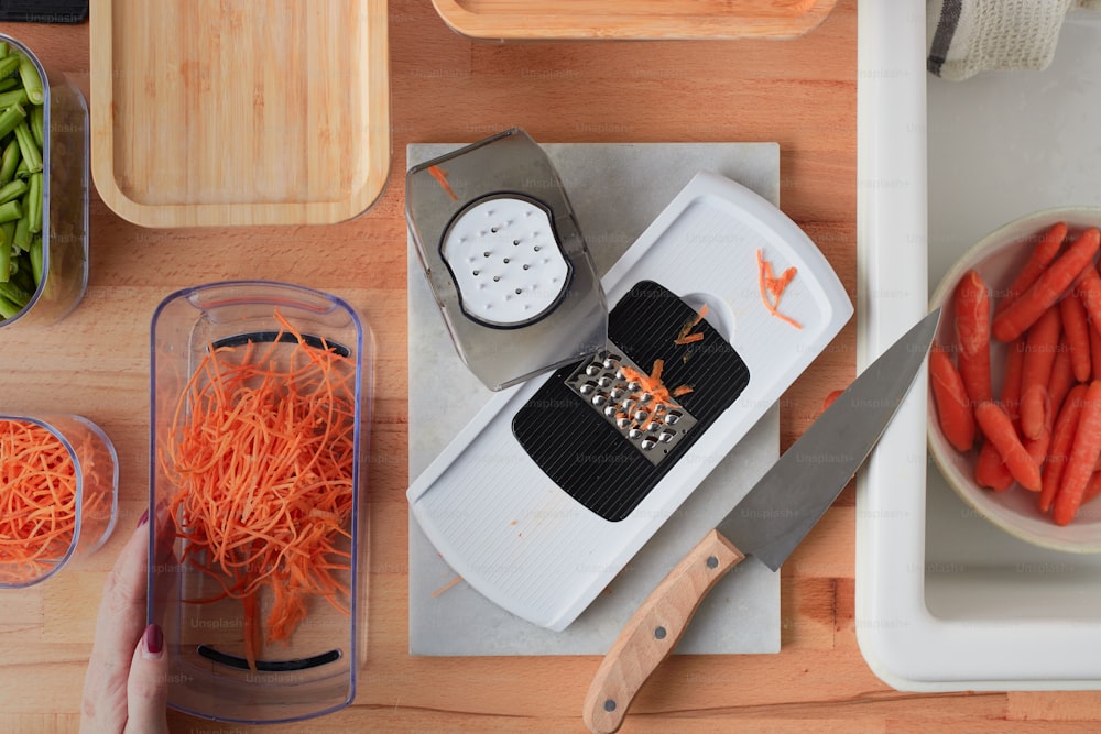una tabla de cortar cubierta con zanahorias y un rallador