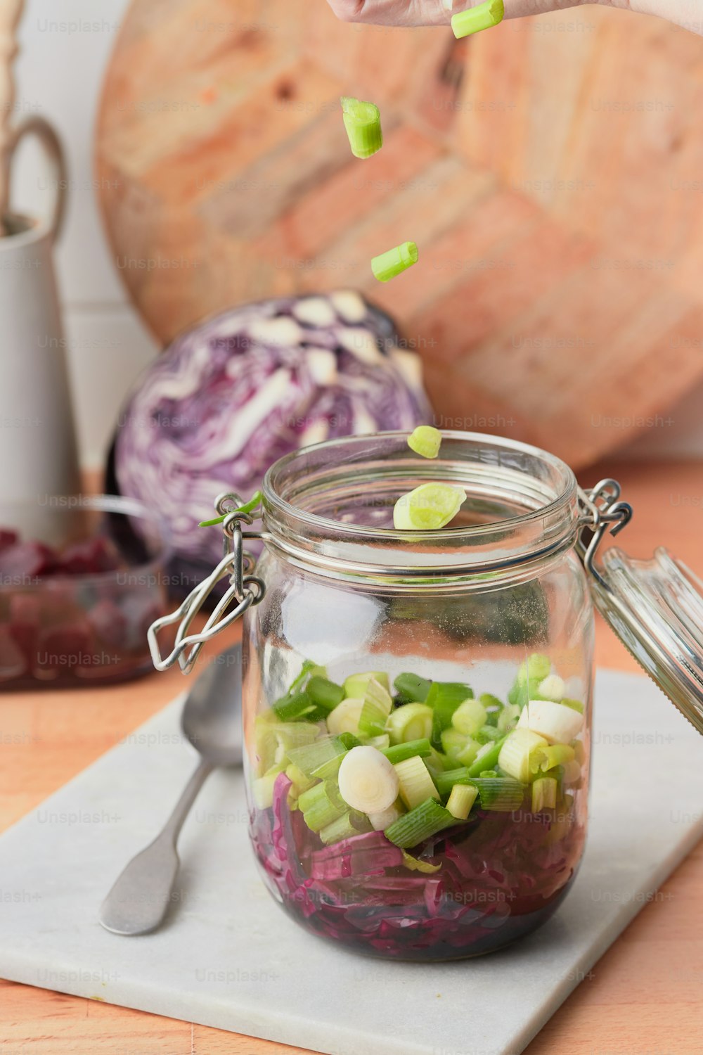 a person is sprinkling chopped vegetables into a jar